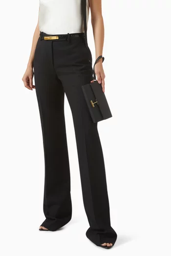 حقيبة صغيرة بحمالة معصم وغطاء قلاب بشعار حرف T جلد